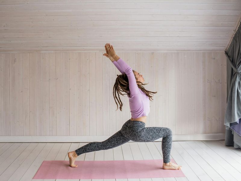 Woman performing a fluid yoga sequence in a bright, modern studio.