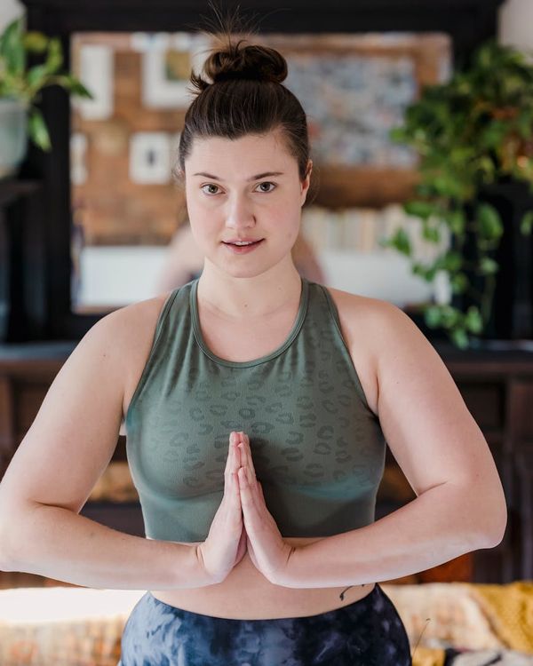 Woman holding a serene yoga pose in a dark room with azure light accents.